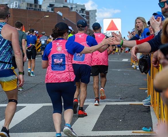 Three DFMC runners pass by enthusiastic supporters