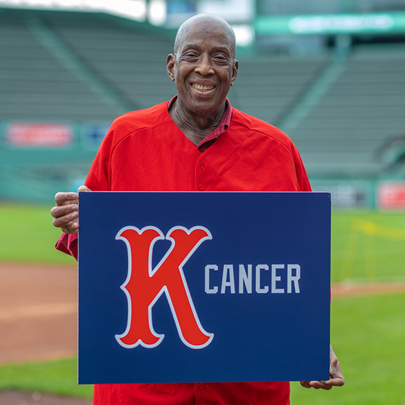 A man holds up a Strike Out Cancer sign in Fenway Park