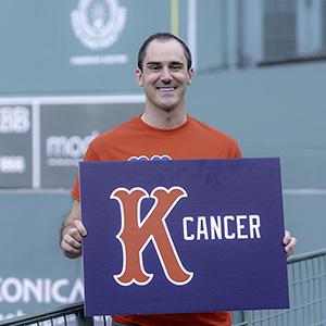 A man holds up a Strike Out Cancer sign in Fenway Park