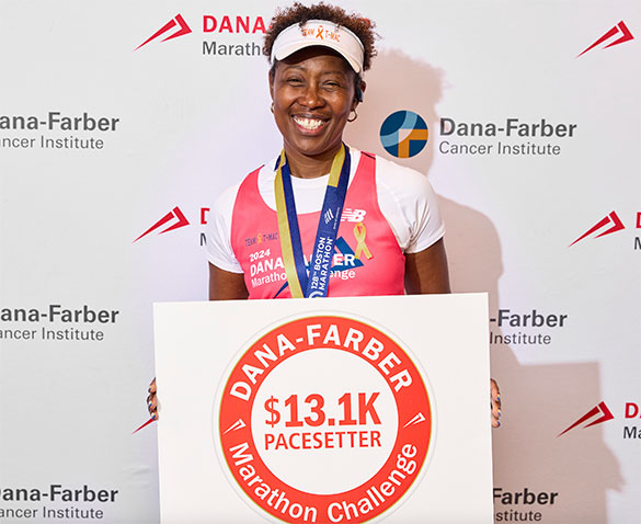 A DFMC finisher with medal and a $13,100 pacesetter sign