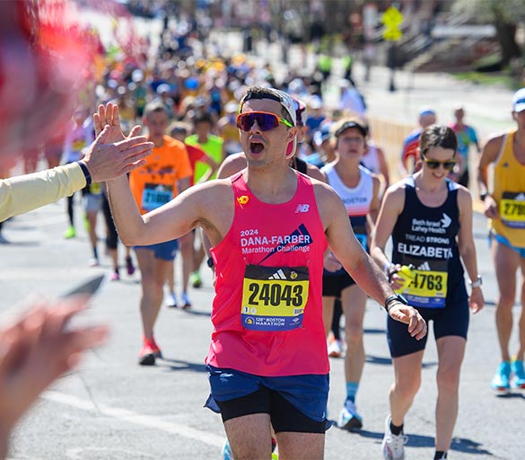 A Dana-Farber Marathon Challenge runner high-fives a supporter