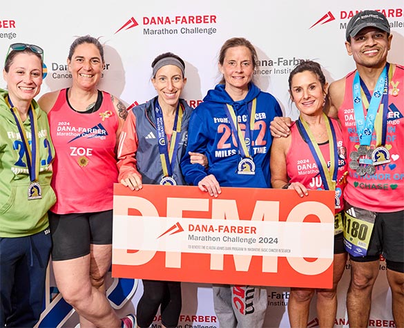 Dana-Farber Marathon Challenge runners with their medals and holding a DFMC sign after the race