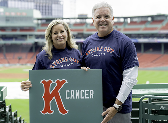 Two friends hold a “strike out cancer” sign at Fenway Park