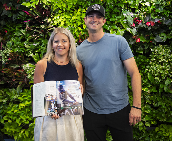Garrett Whitlock stands next to a woman holding a magazine spread with his autograph