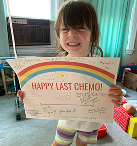 Tilly, a Dana-Farber Jimmy Fund patient holding a Happy Last Chemo sign