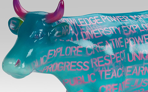 Teal mini cow covered in pink words close-up