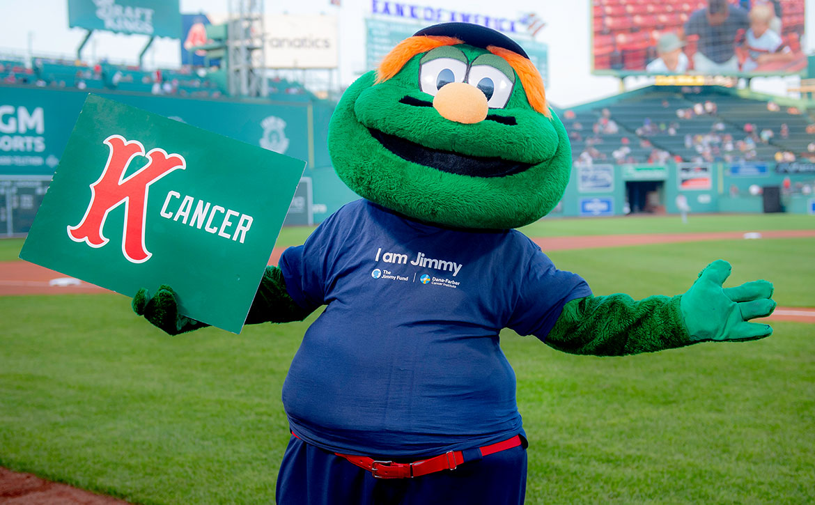 Wally the Green Monster holding a 'K Cancer' sign at Fenway Park